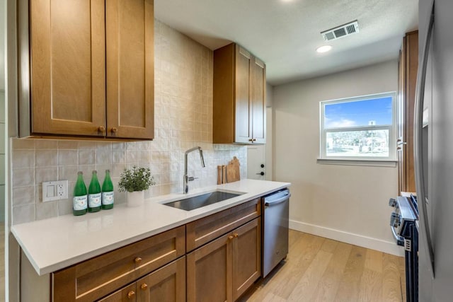 kitchen with tasteful backsplash, visible vents, appliances with stainless steel finishes, a sink, and baseboards