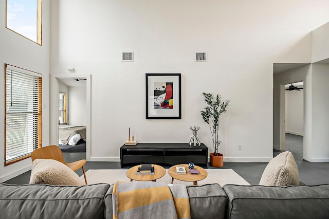 living room featuring visible vents, a towering ceiling, and baseboards