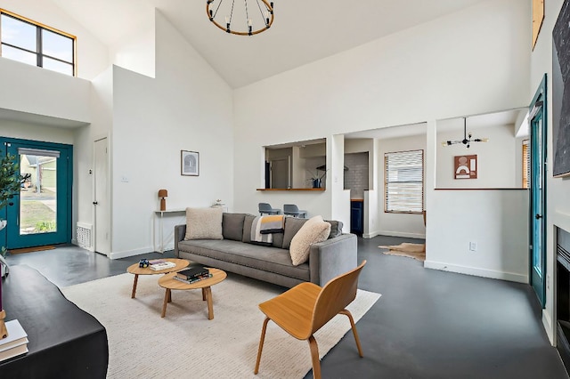 living room featuring high vaulted ceiling, a notable chandelier, finished concrete flooring, and baseboards