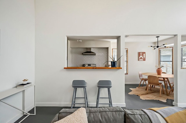 kitchen featuring baseboards, range, wall chimney exhaust hood, and an inviting chandelier