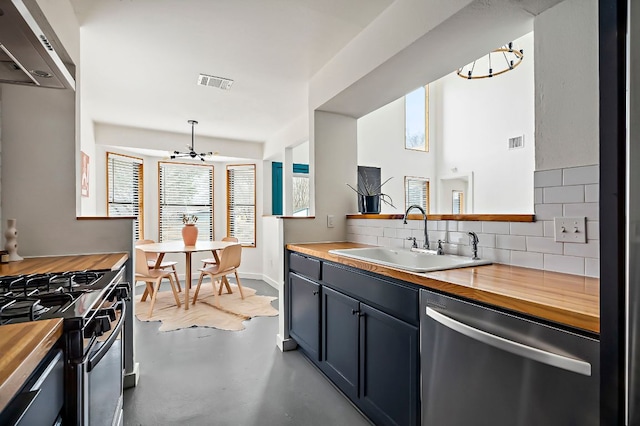 kitchen with visible vents, decorative backsplash, butcher block countertops, stainless steel dishwasher, and a sink