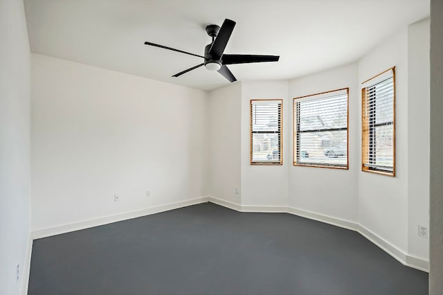 empty room featuring ceiling fan, finished concrete floors, and baseboards