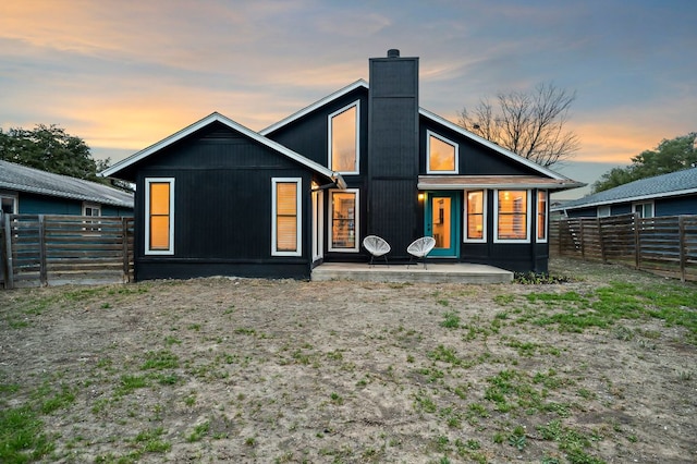 back of house with a patio area, a chimney, and fence