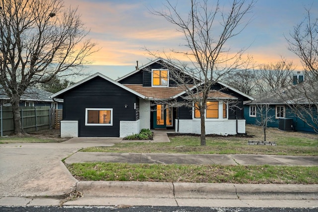 view of front of home with concrete driveway, brick siding, central AC, and fence