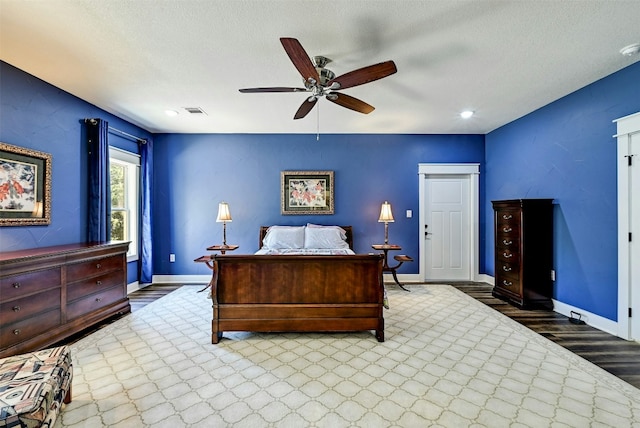 bedroom featuring visible vents, baseboards, a textured ceiling, and wood finished floors