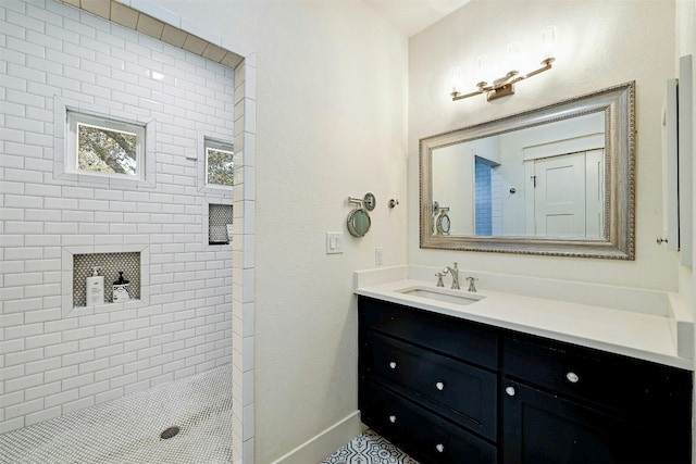 bathroom featuring baseboards, tiled shower, and vanity