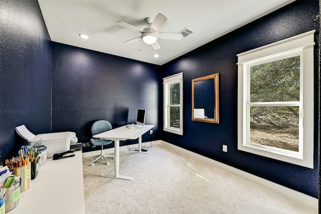 carpeted office featuring a ceiling fan, visible vents, a textured wall, and baseboards