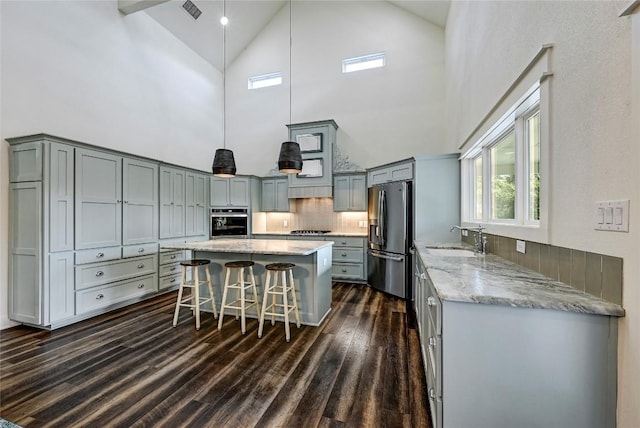 kitchen with a sink, a kitchen island, appliances with stainless steel finishes, and gray cabinets
