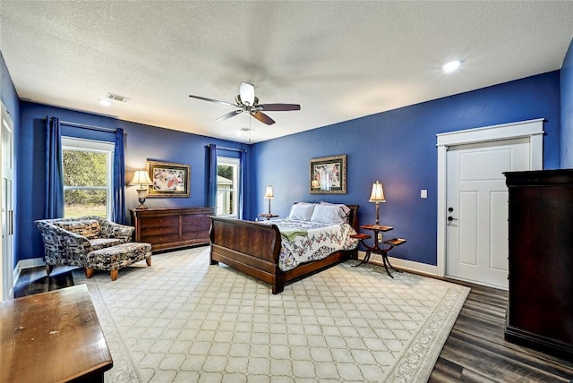 bedroom featuring visible vents, multiple windows, a textured ceiling, and baseboards