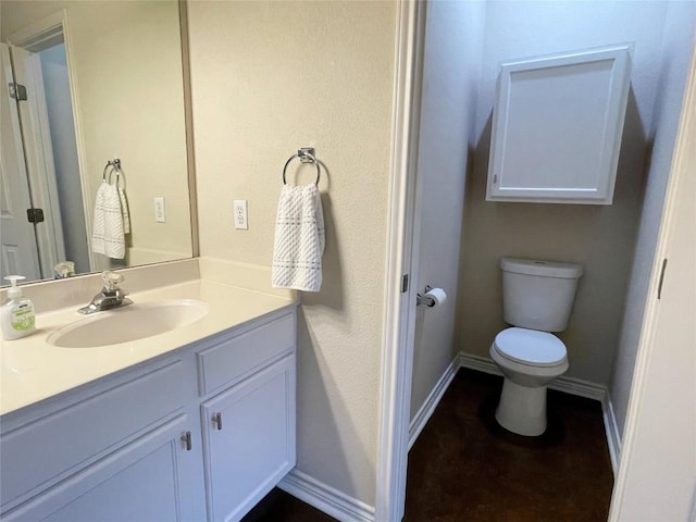 bathroom featuring toilet, vanity, and baseboards