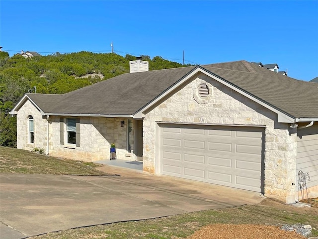 view of front of home featuring a garage, roof with shingles, driveway, and a chimney