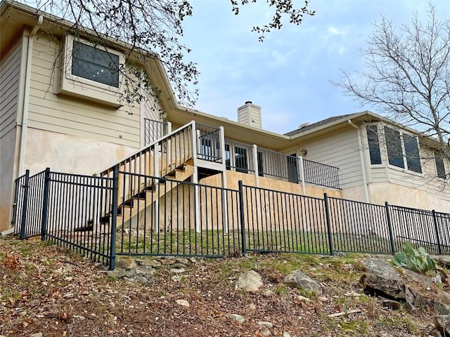 exterior space featuring stairs, a chimney, and fence