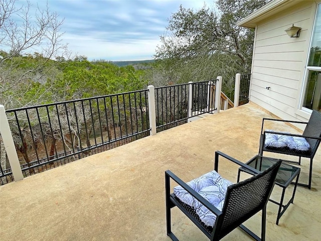 view of patio / terrace featuring a wooded view and a balcony