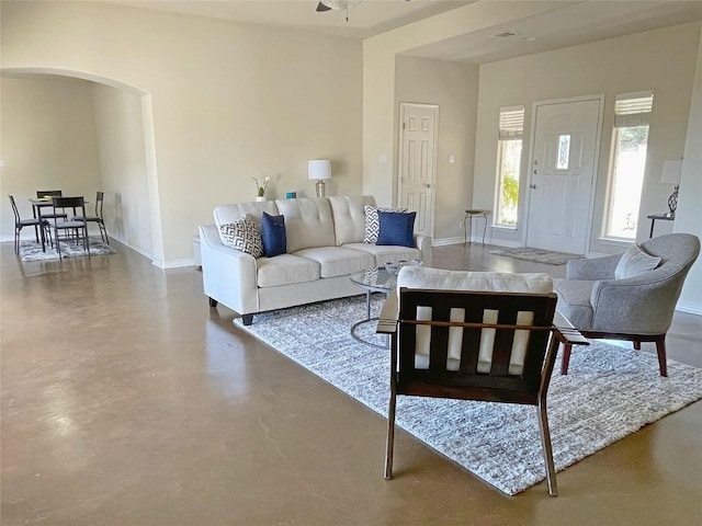 living room with concrete flooring, arched walkways, and baseboards