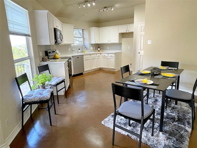 kitchen featuring appliances with stainless steel finishes, a sink, finished concrete floors, and white cabinets