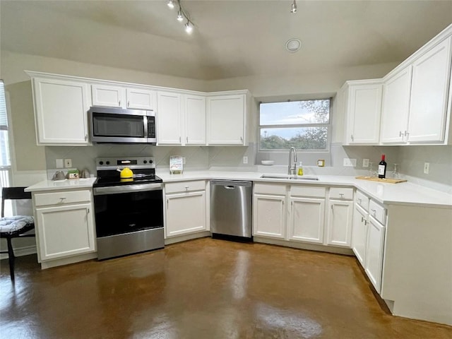 kitchen with decorative backsplash, appliances with stainless steel finishes, white cabinetry, a sink, and concrete flooring