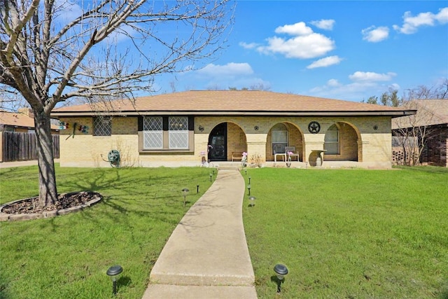 ranch-style house with brick siding, fence, a front lawn, and roof with shingles