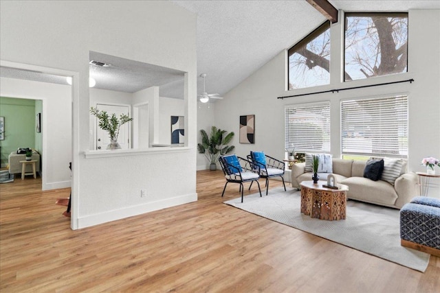 living area with wood finished floors, baseboards, visible vents, a textured ceiling, and beamed ceiling