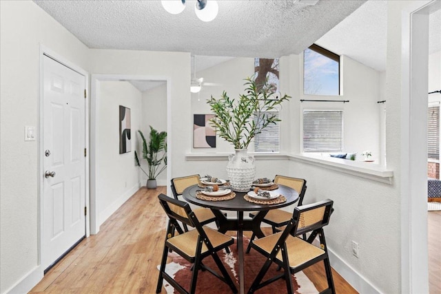 dining space featuring wood finished floors, baseboards, and a textured ceiling