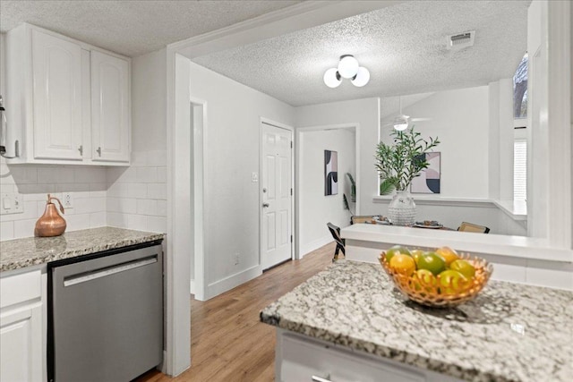 kitchen with light wood-type flooring, visible vents, tasteful backsplash, white cabinets, and dishwasher