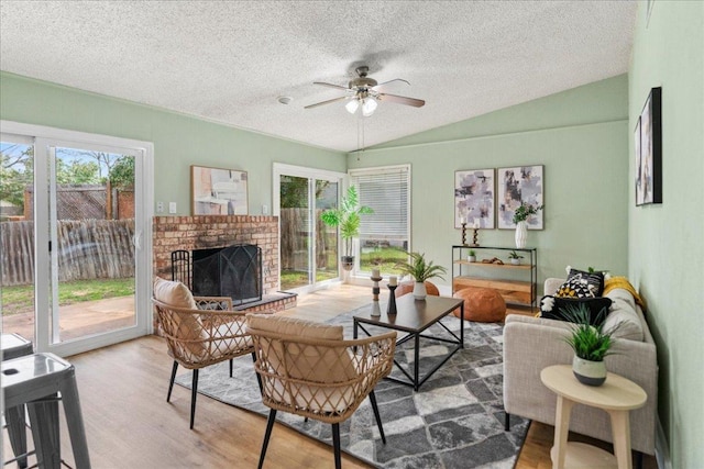 living area featuring a fireplace, lofted ceiling, plenty of natural light, and wood finished floors