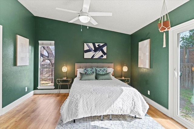 bedroom with multiple windows, lofted ceiling, baseboards, and wood finished floors