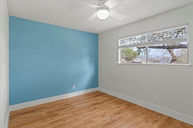 empty room with ceiling fan, baseboards, a textured ceiling, and light wood-style flooring