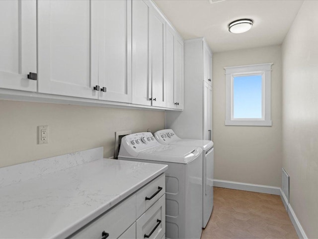 washroom featuring washer and dryer, baseboards, cabinet space, and visible vents