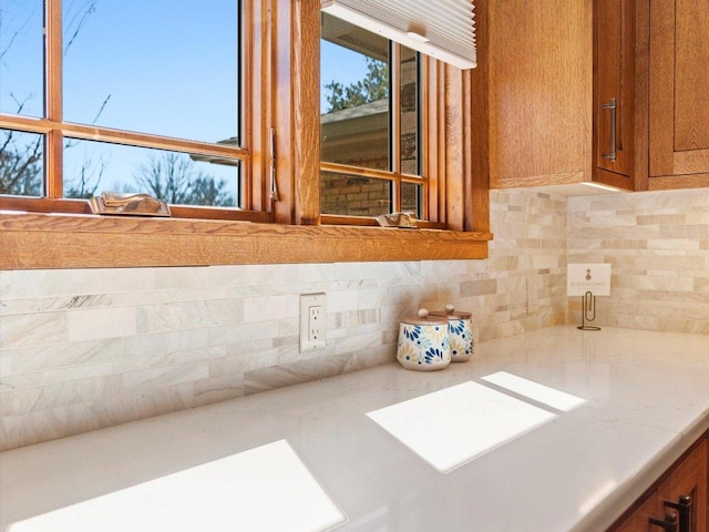 room details with brown cabinetry, backsplash, and light countertops