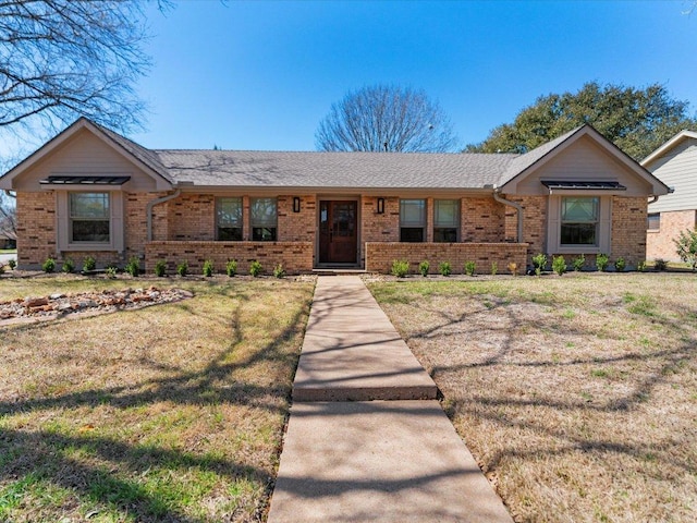 single story home featuring brick siding, a front yard, and roof with shingles