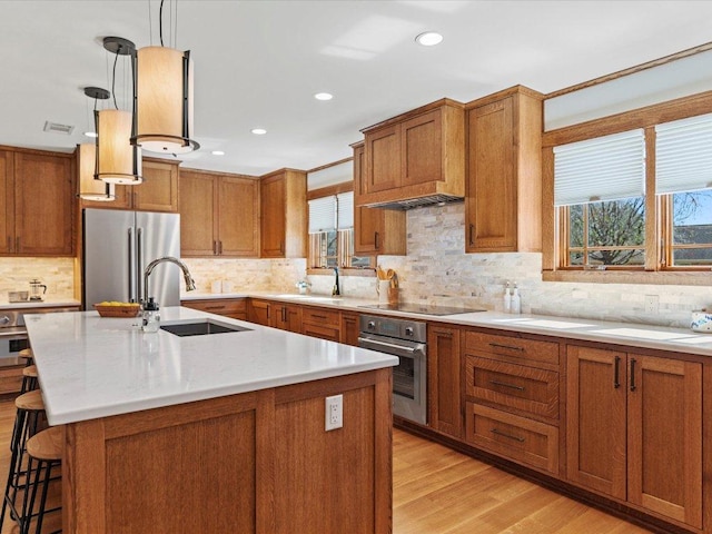 kitchen featuring a sink, stainless steel appliances, and brown cabinetry