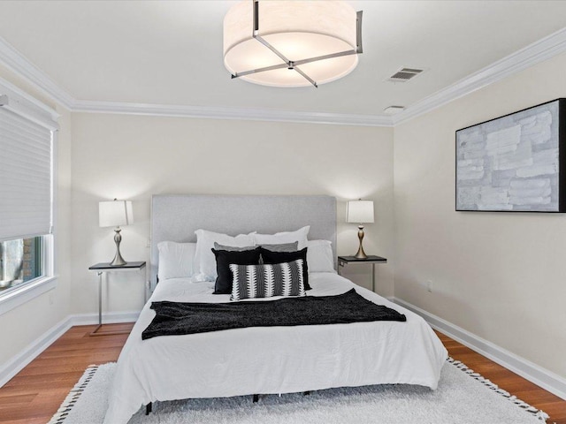 bedroom featuring crown molding, wood finished floors, and visible vents