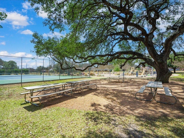 view of community with a tennis court and fence