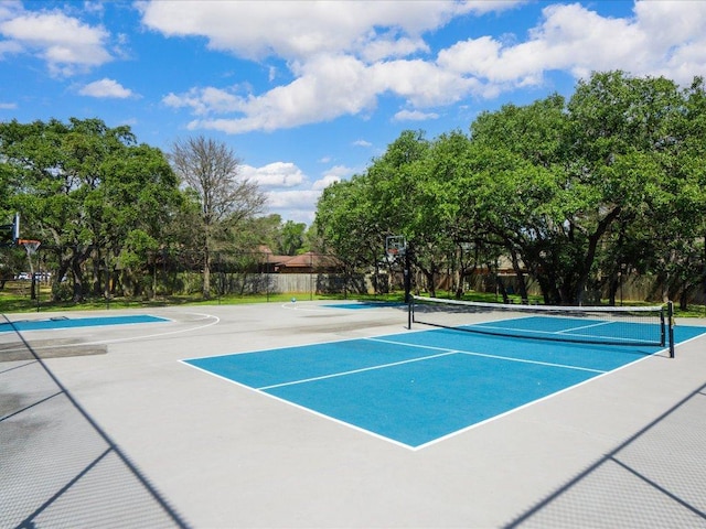 view of tennis court with community basketball court and fence