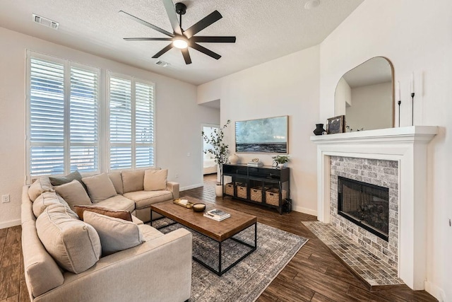 living room featuring visible vents, a ceiling fan, wood finished floors, a textured ceiling, and a fireplace