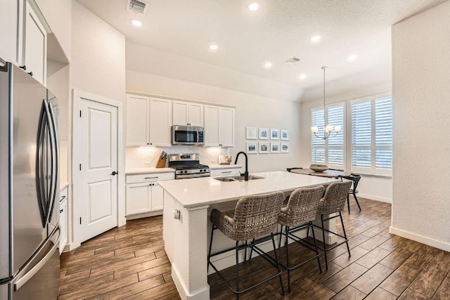 kitchen featuring stainless steel appliances, wood finish floors, visible vents, and a sink