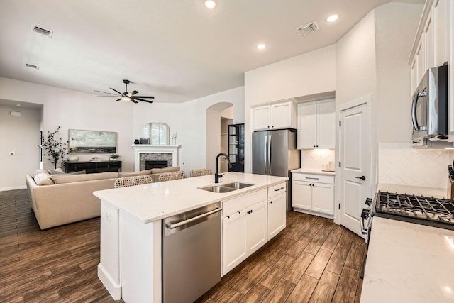 kitchen featuring a stone fireplace, dark wood-style flooring, a sink, visible vents, and appliances with stainless steel finishes