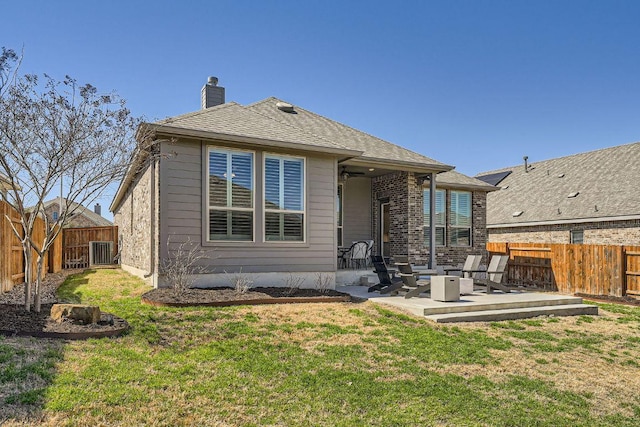 back of property featuring a yard, a chimney, a patio area, and a fenced backyard