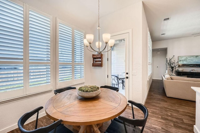 dining room with baseboards, wood finished floors, visible vents, and an inviting chandelier