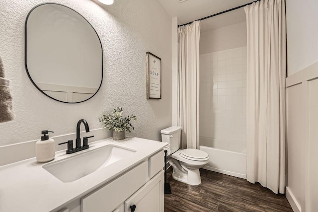 full bath with a textured wall, toilet, wood finished floors, vanity, and shower / bathtub combination with curtain