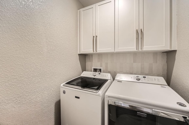 washroom with cabinet space, a textured wall, and washing machine and clothes dryer