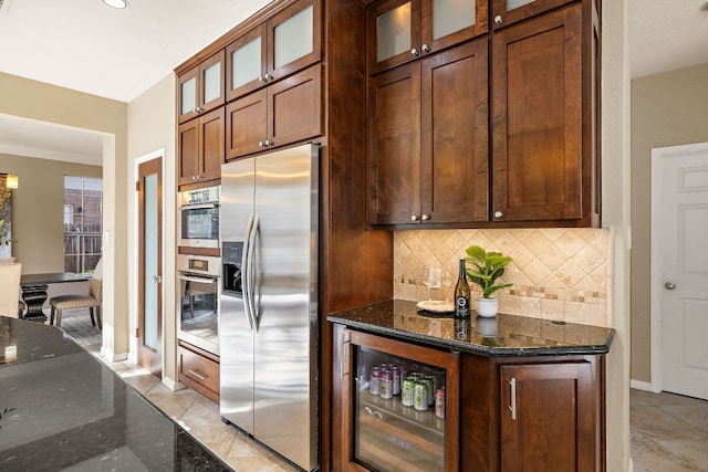 kitchen with dark stone countertops, beverage cooler, appliances with stainless steel finishes, and backsplash