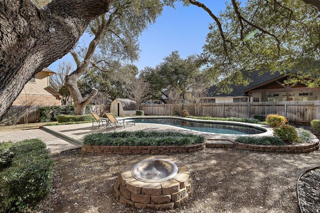 view of pool featuring a fire pit, a fenced in pool, a patio, a fenced backyard, and an outdoor structure