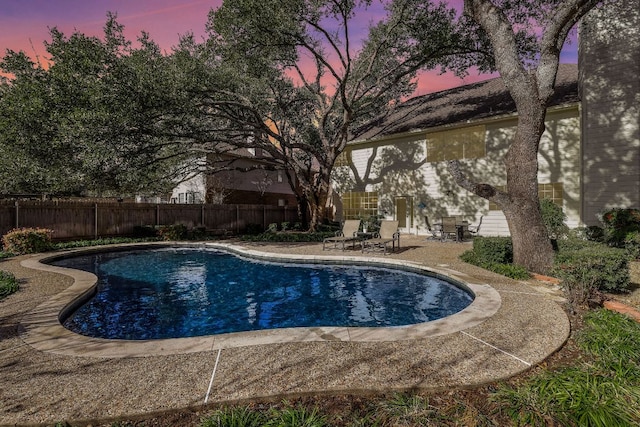 pool at dusk featuring a fenced backyard, a fenced in pool, and a patio