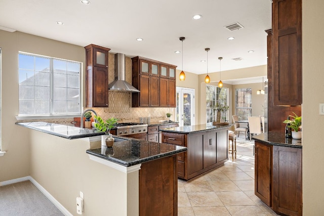 kitchen with visible vents, wall chimney range hood, a center island, tasteful backsplash, and plenty of natural light