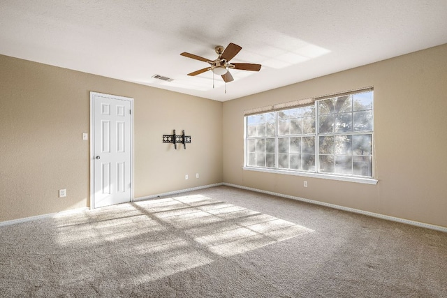 carpeted empty room with a ceiling fan, visible vents, a textured ceiling, and baseboards