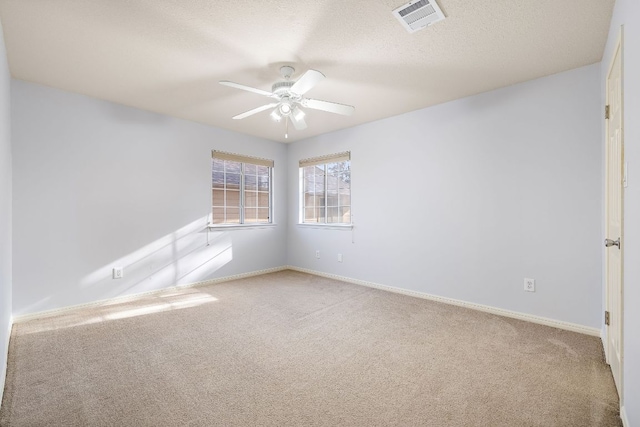 carpeted empty room featuring a ceiling fan, visible vents, a textured ceiling, and baseboards