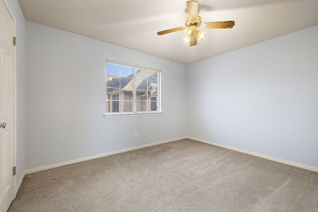 carpeted empty room with a textured ceiling, a ceiling fan, and baseboards