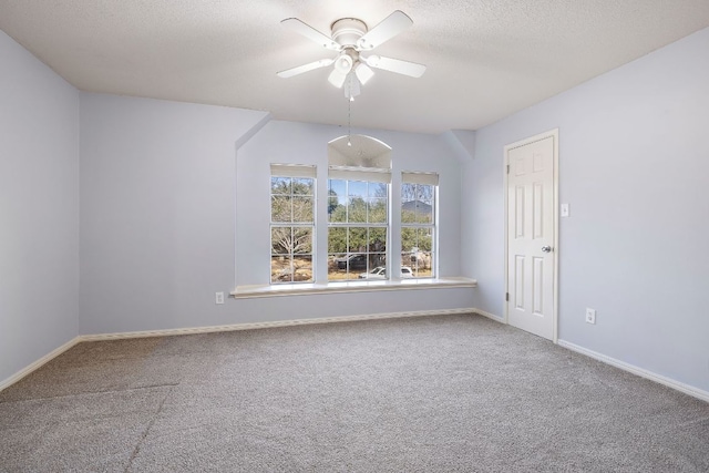 carpeted spare room with a textured ceiling, ceiling fan, and baseboards