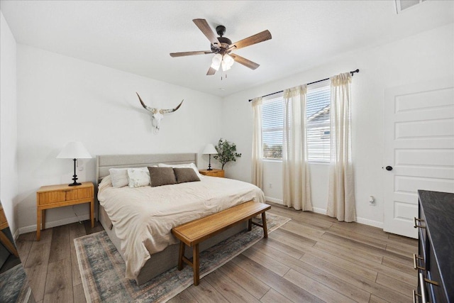 bedroom with ceiling fan, visible vents, baseboards, and light wood-style flooring
